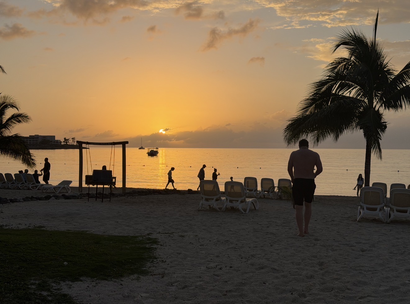 Sunset over the ocean at Riu Palace Tropical Bay in Negril, Jamaica, with palm trees and beach loungers