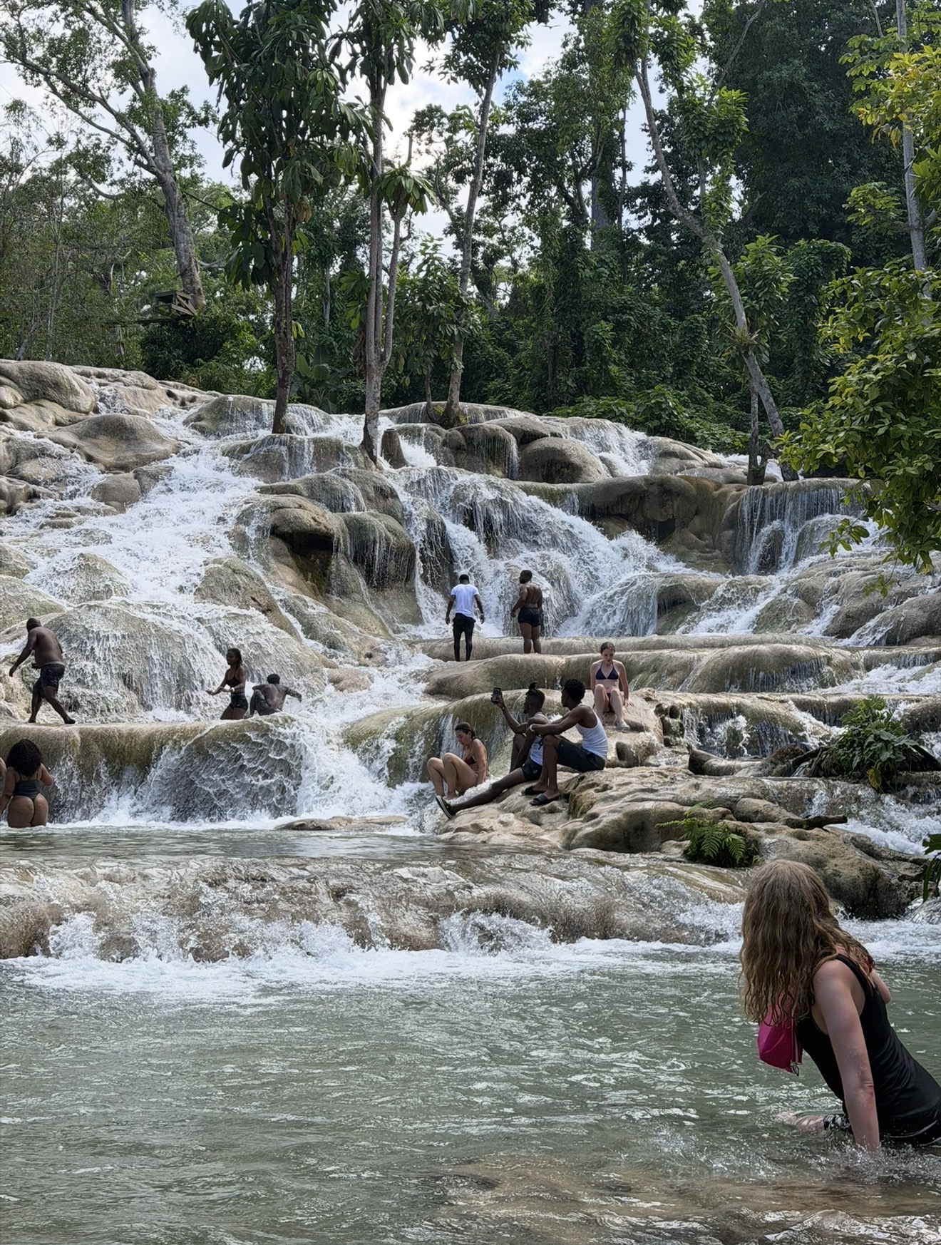 Climbers making their way up the cascading rock terraces of Dunn's River Falls in Ocho Rios, Jamaica