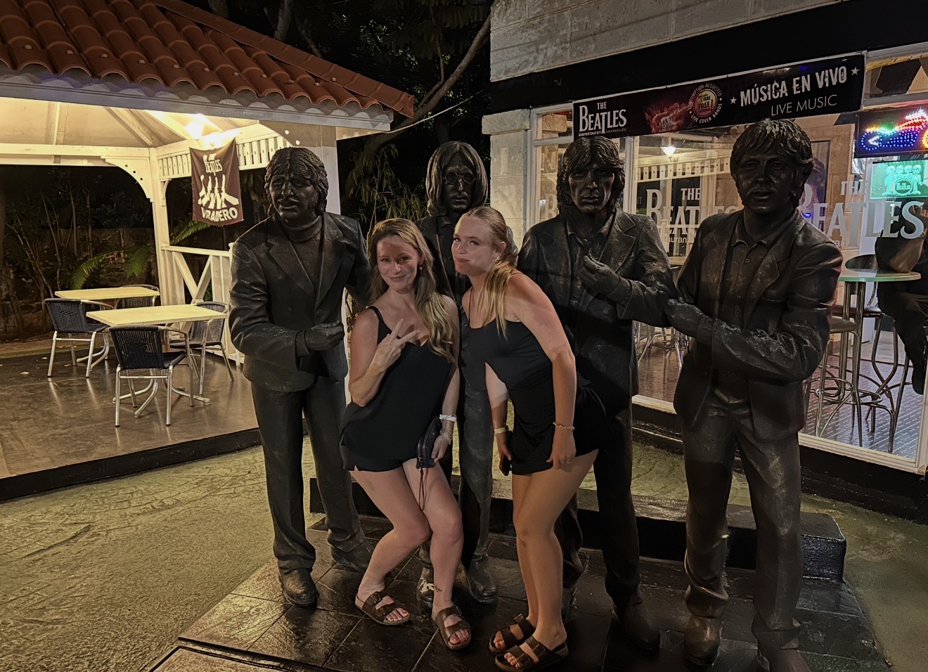 Two women posing with bronze Beatles statues outside a bar in Varadero, Cuba