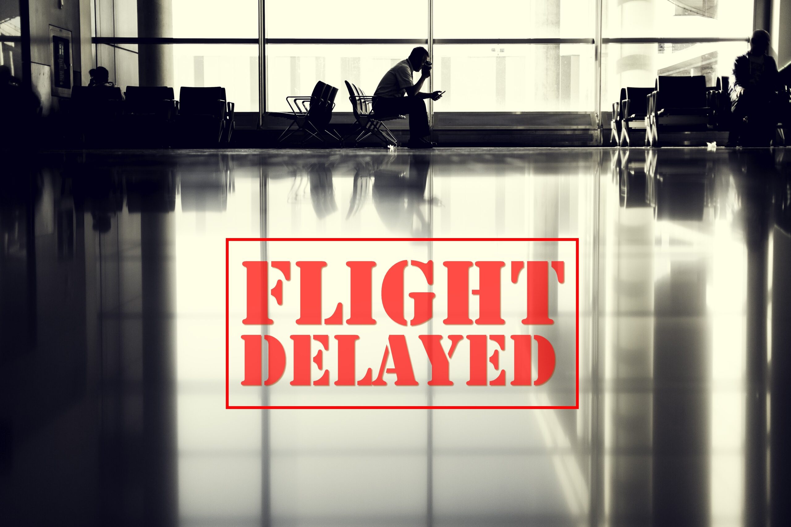 Silhouette of a man waiting at an airport gate with a FLIGHT DELAYED stamp overlay