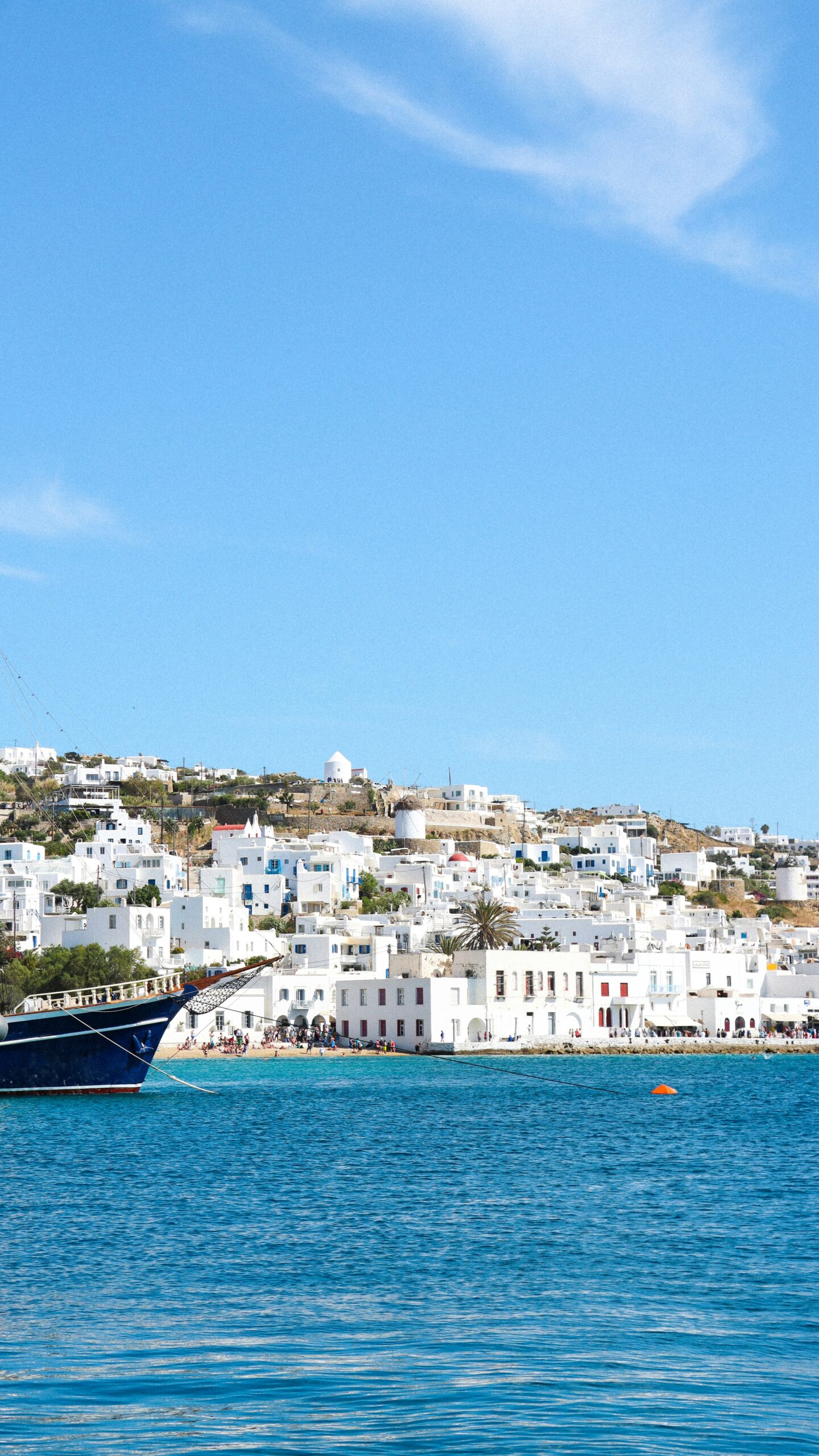 Boat in the harbor at Mykonos, Greece, with whitewashed buildings along the waterfront